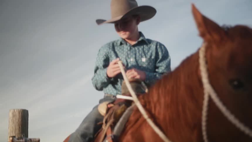 A young cowboy sits on a horse