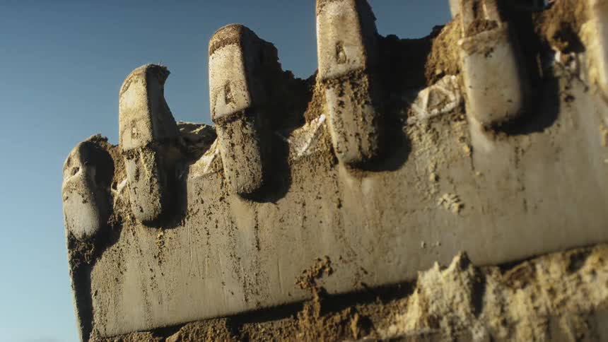 Dirt clings to digger claws on sunny day