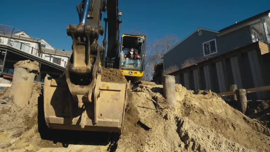 Man uses a backhoe to dig dirt out for a foundation