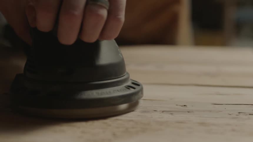 A person is sanding a plank of wood