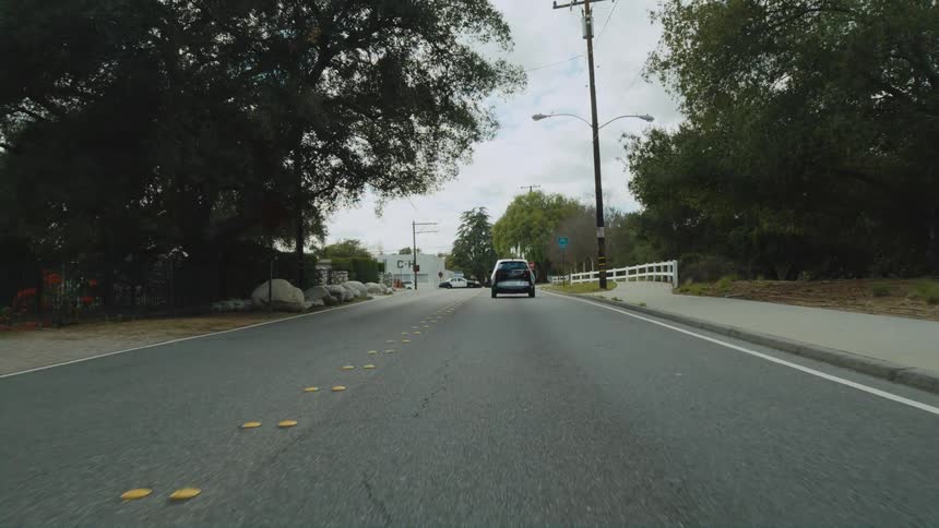 A vehicle travels down a road in a town on a cloudy day