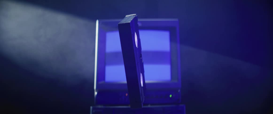 Vhs tape suspended in the air spinning in front of a vintage television screen under a spotlight