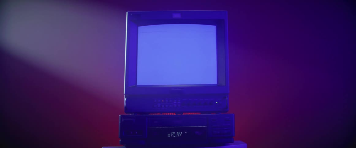 A smal tube style television sits atop a vcr