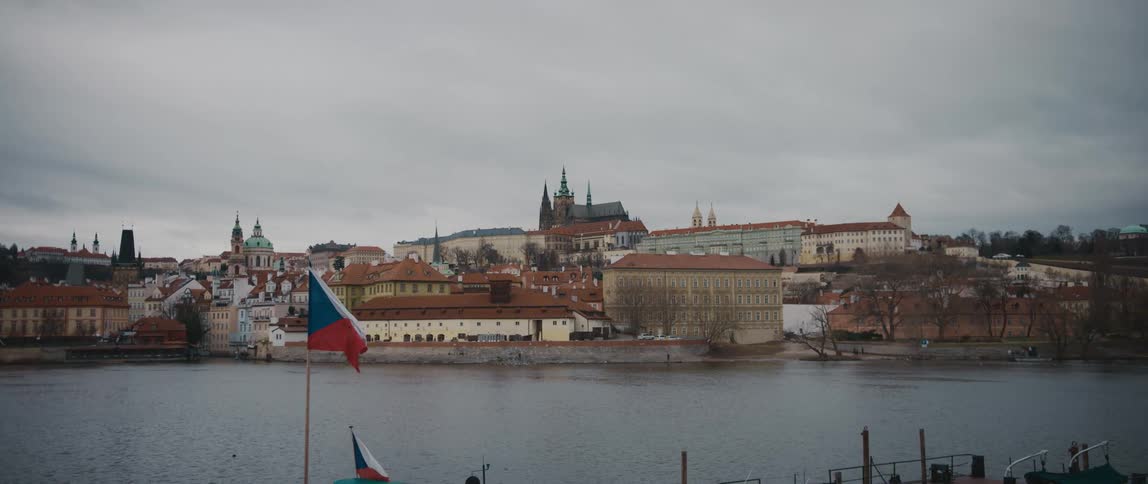 A flag flies along the river across from a city