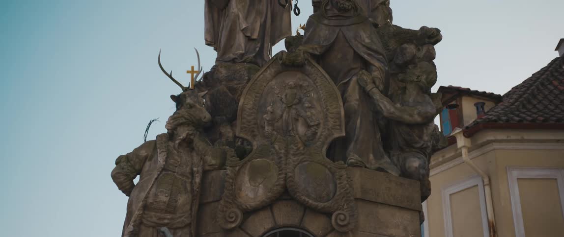 Monument with statues holding handcuffs a large knife and a gold colored cross sits under a blue sky