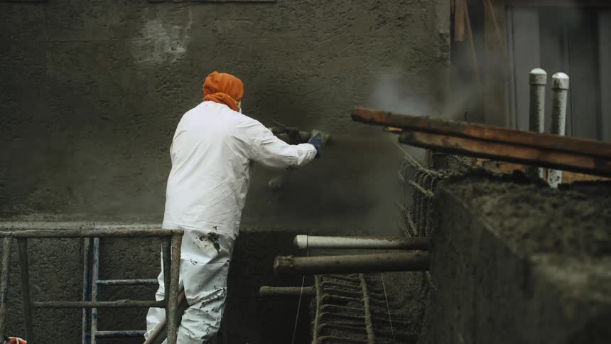 A man power washes the side of a stone building