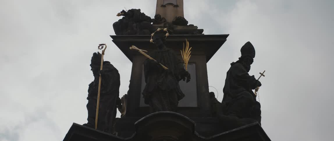 Religious statuary made of stone and metal stands against cloudy sky
