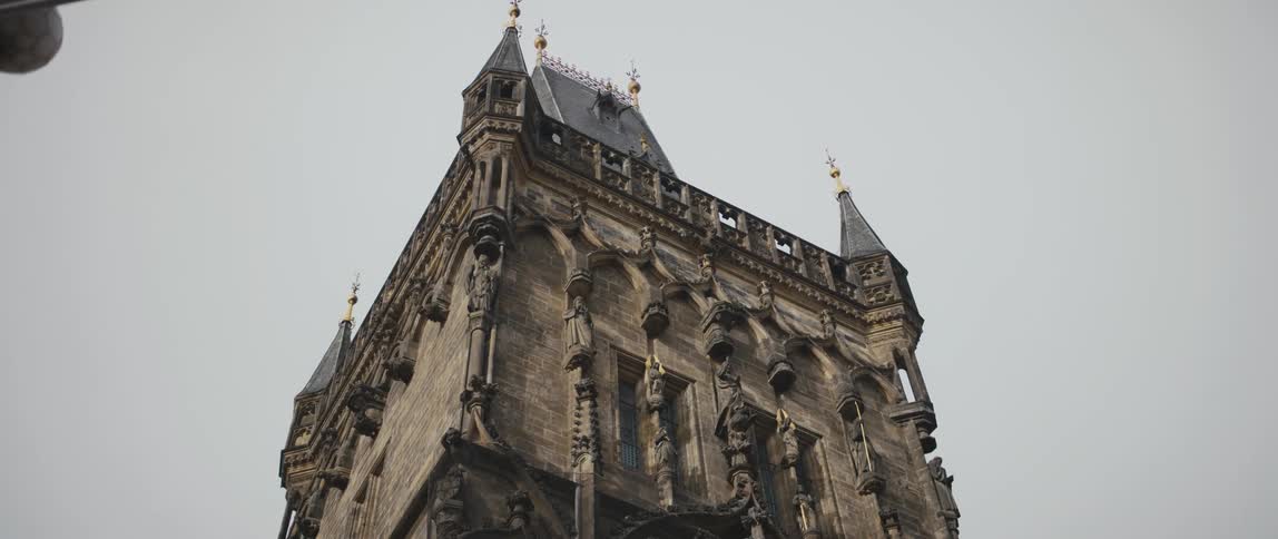 Ornate designs and statues on the side of a tall building under a cloudy sky