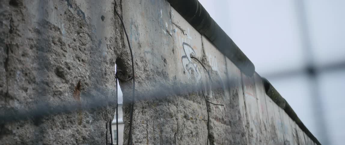A section of the Berlin Wall memorial with remnants of graffiti and bullet holes from time past.