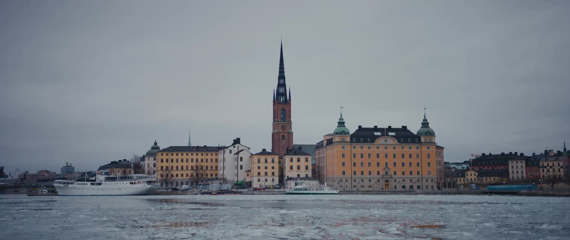 Boats in a frozen harbor in front of buildings on a winter day