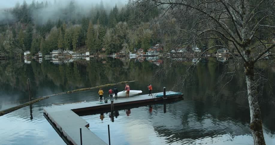 People standing on a dock lower another canoe into the water