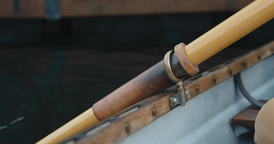 A person uses oars to row a boat down a river