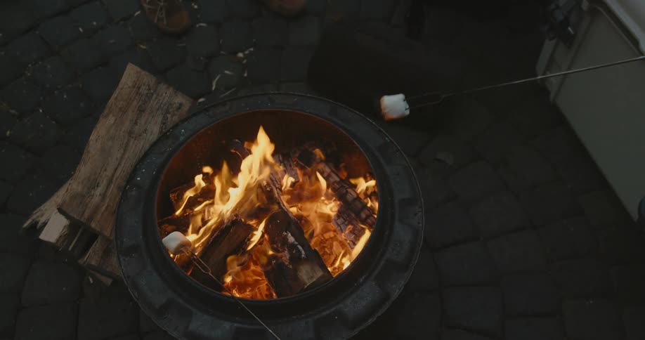 Marshmallows are toasted over the flames of a backyard fire pit