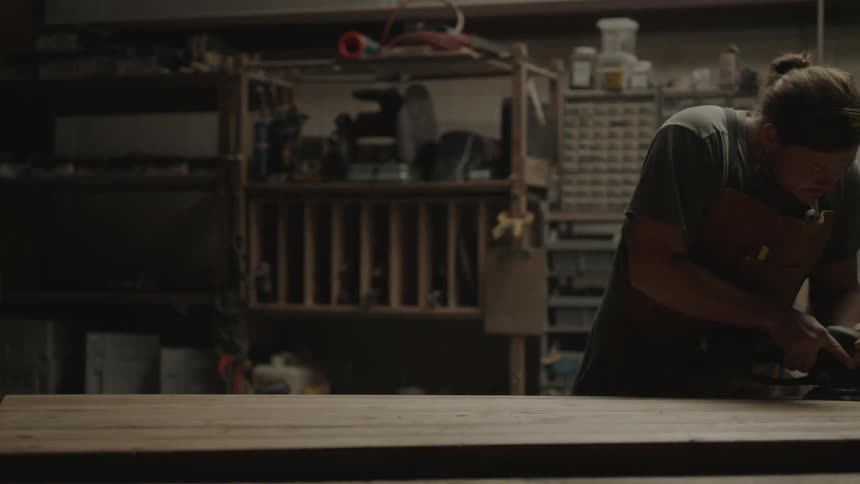 A man is sanding a board of wood
