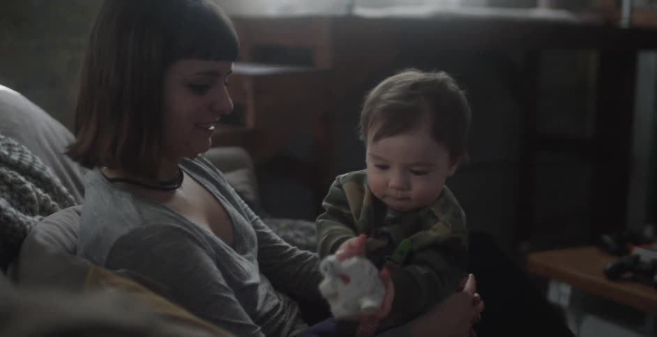 A baby is playing with a toy on a woman's lap
