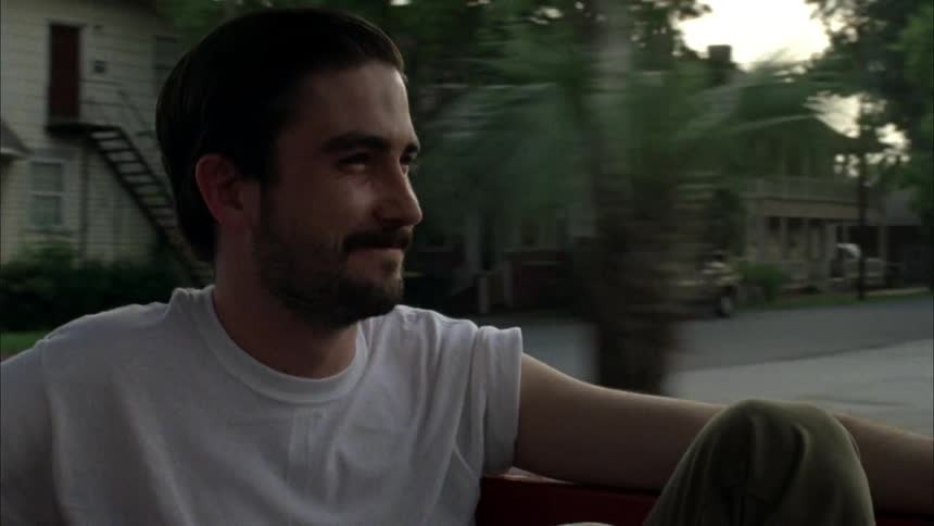 A man is smiling as he rides in the back of a moving vehicle