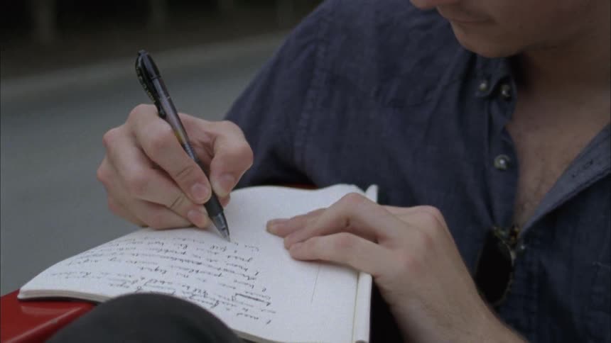 A man is writing while riding in the back of a pickup truck