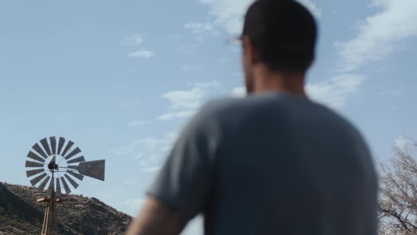 A man stands outside and looks at a windmill