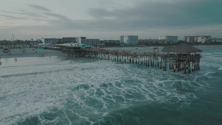 People walking on the beach and playing in the ocean as waves roll in