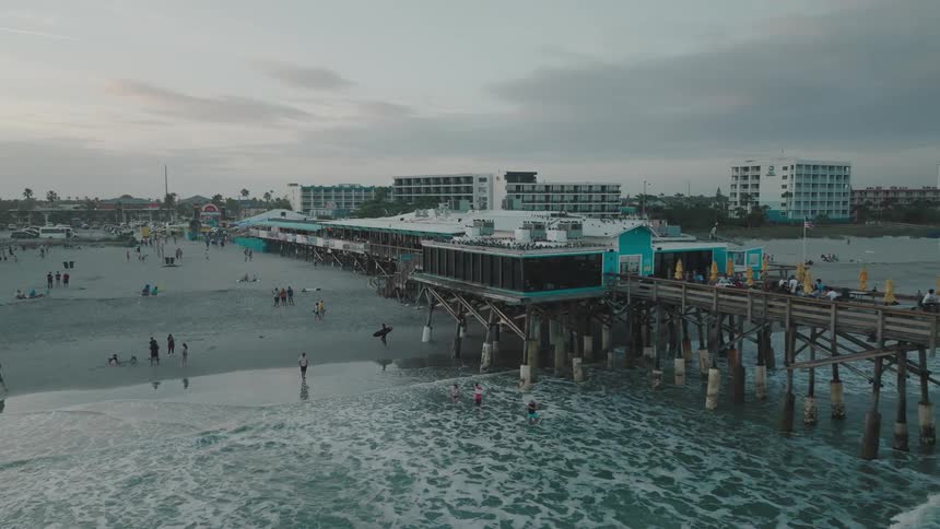 People walking on the beach and playing in the water with hotels in the background