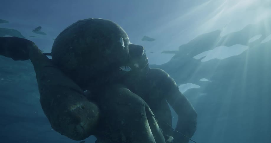 The sun shines on statue of man underwater