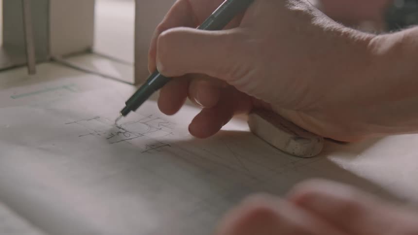 Someone is holding a pen in their right hand and writing on paper