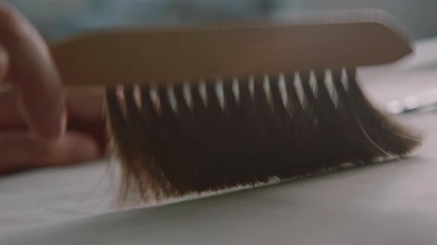 A man in an office brushes off a piece of a paper with a drawing on it