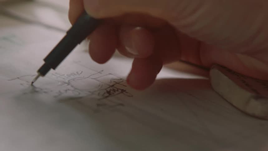 Someone is holding a pen in their right hand and writing on paper