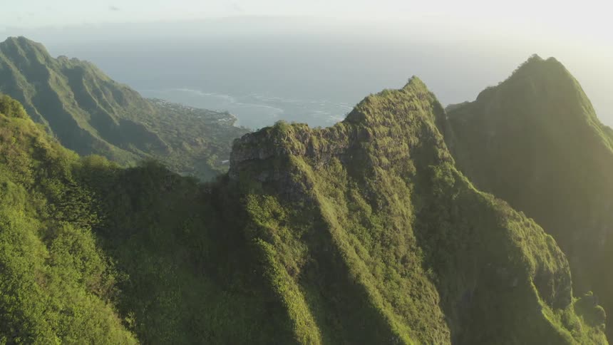 Mountain ridge and valley covered with green grass and plants under a hazy sky