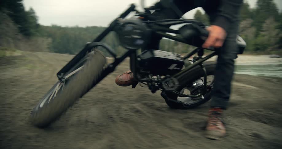A male spins his bike in circles next to a river