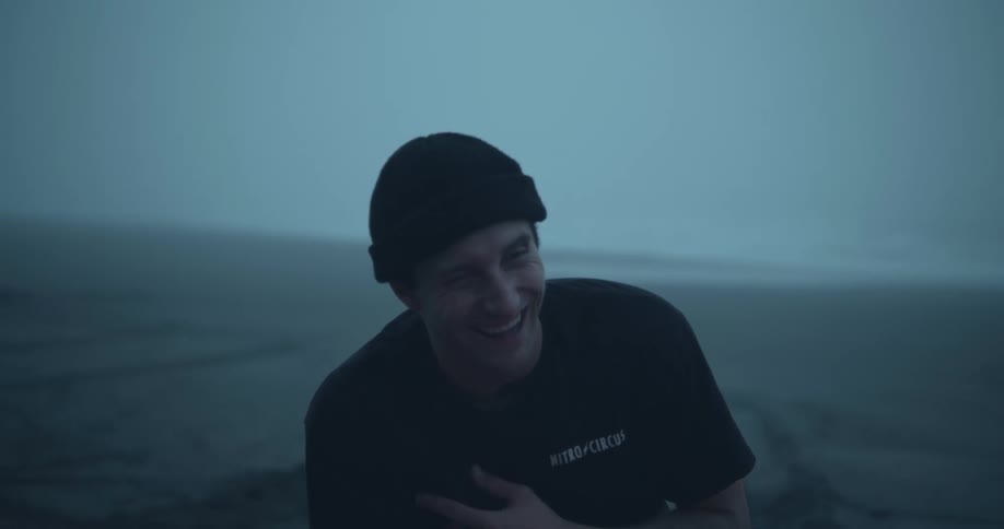 A man sits outside and grabs his chest as he laughs