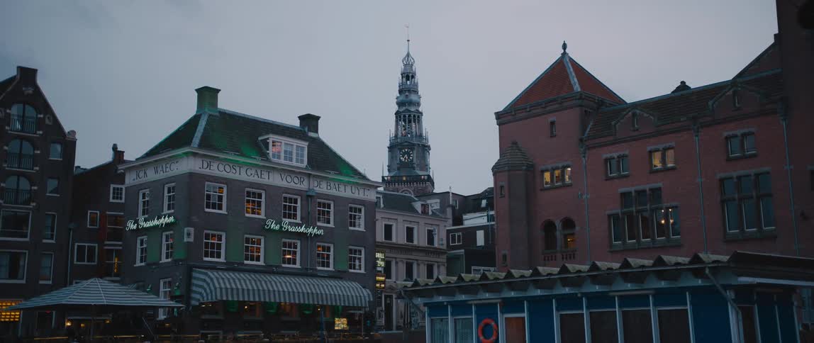 A bird flies past the The Grasshopper, Beurs van Berlage, and the Oude Kerk Church bell tower in Amsterdam.
