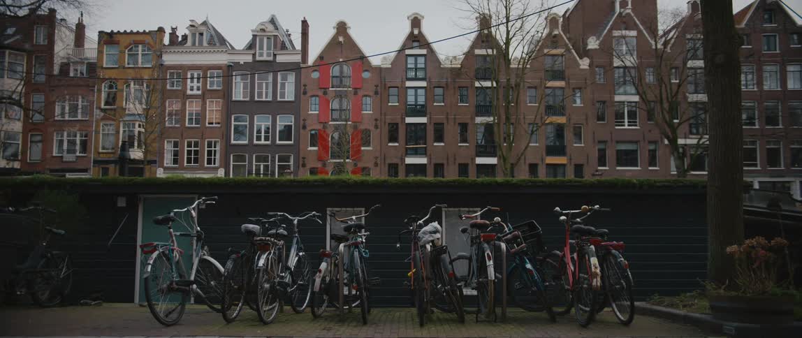 Bicycles parked near doorways with canal homes of Amsterdam behind