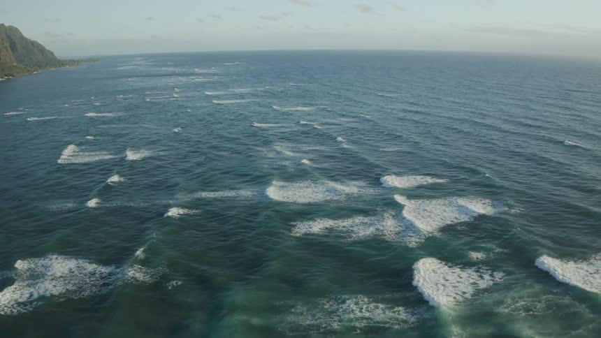 An aerial view of waves rolling towards the shore in the ocean