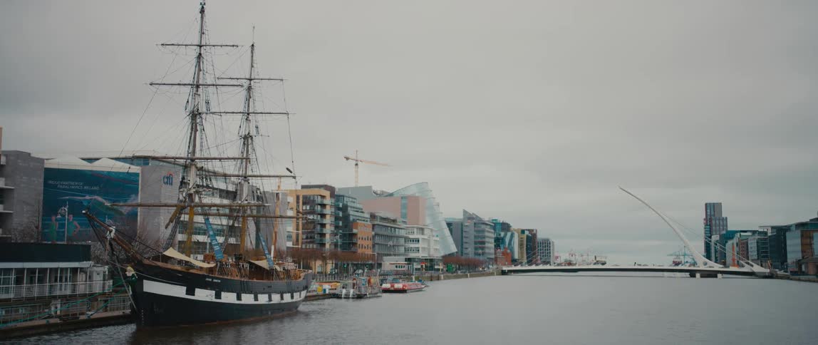 The Jeanie Johnston three-masted replica ship moored off Custom House Quay on the River Liffey in Dublin, Ireland, with the Samuel Beckett Bridge in the background.