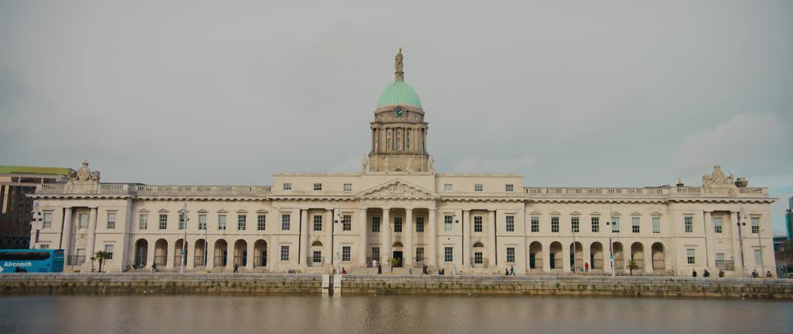 Pedestrians move around The Custom House government building in Dublin, Ireland