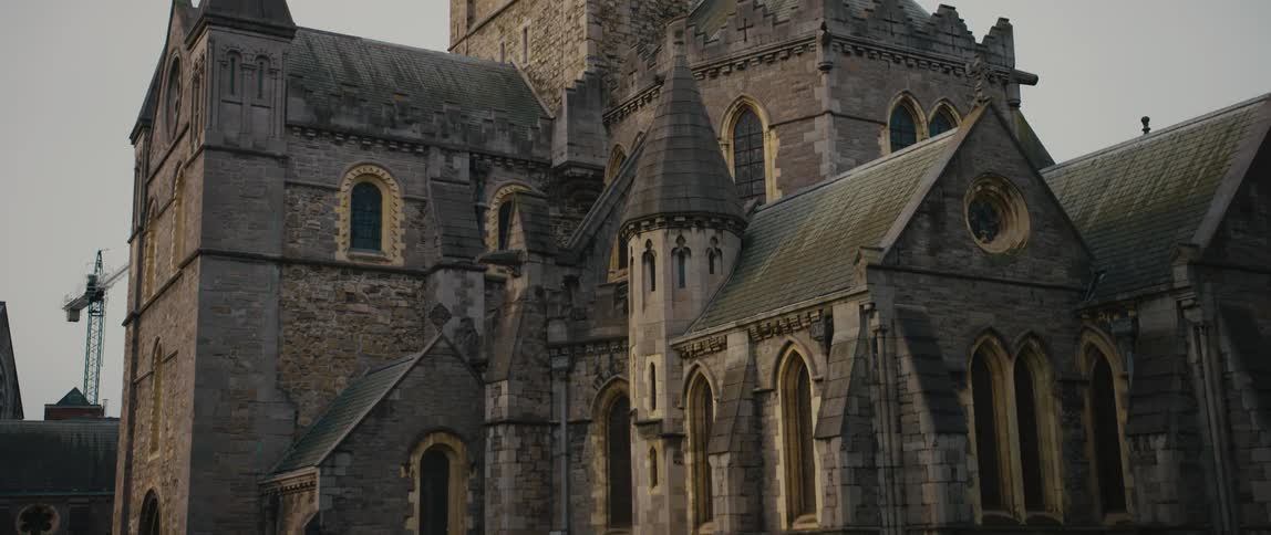 View panning down from the spired tower to the ornate Gothic facade and Jesus the Homeless bench sculpture of Christ Church Cathedral in Dublin, Ireland