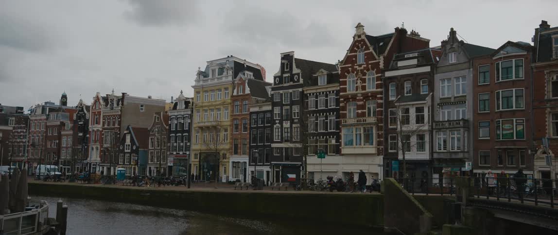 Pedestrians walk along a canal in Amsterdam