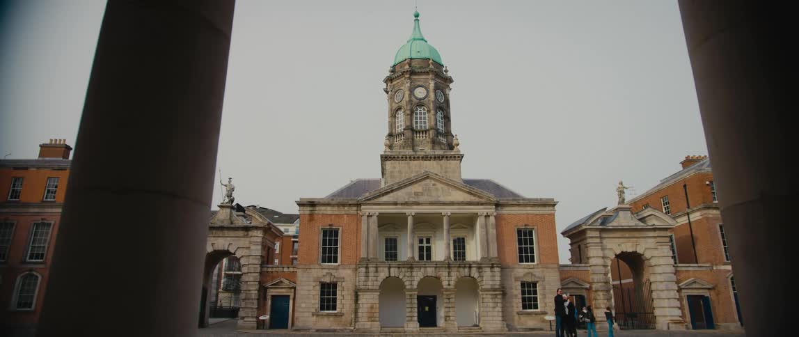 The copper dome, clock tower, arched bays, and corinthian columns of Bedford Hall, flanked by two castle gates, in Dublin Castle, Ireland