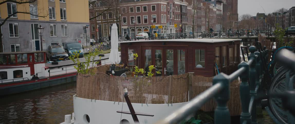 People and vehicles travel over a bridge on a canal in Amsterdam