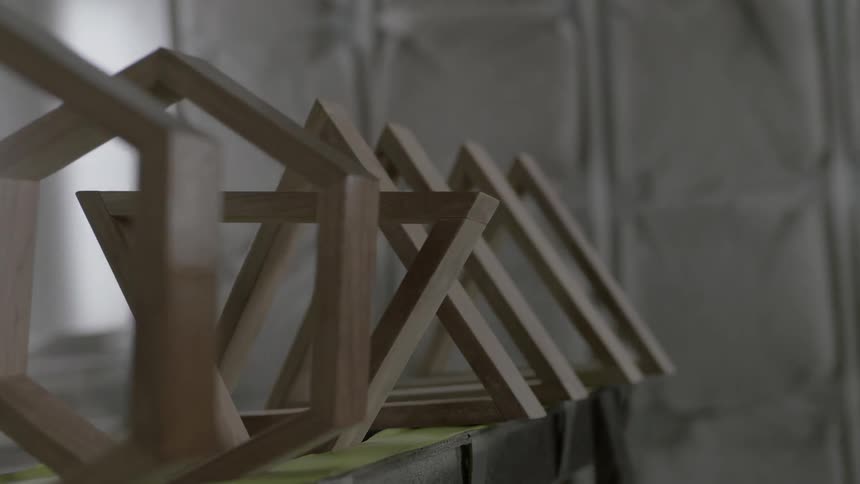 A man is spraying some wood pieces