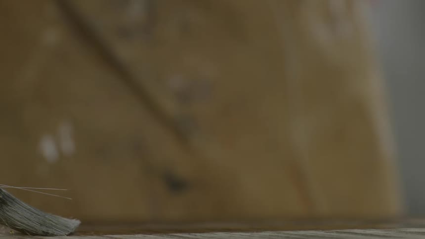 A person is painting with a brush on wood