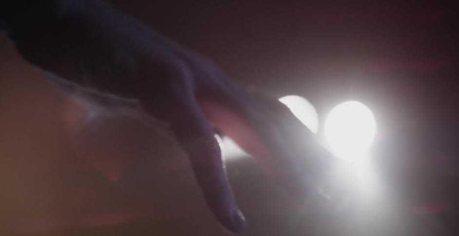 A hand is waving in front of some lights