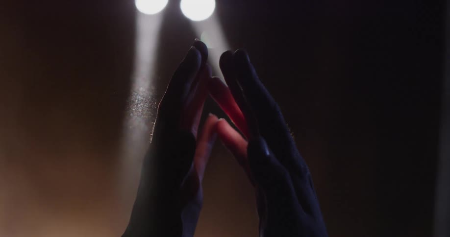 Two hands gently coming together as spotlights shine near to them