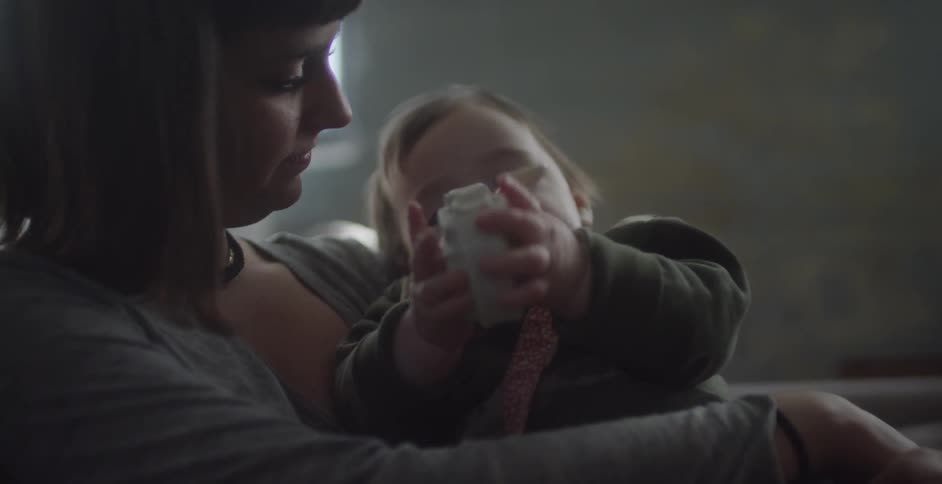Woman holding and watching baby play with toy
