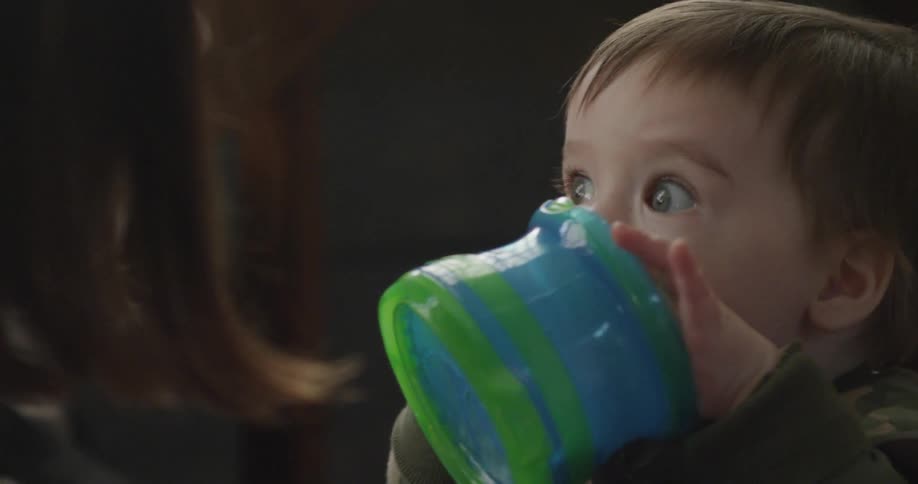 A baby picks up a container and puts it in his mouth