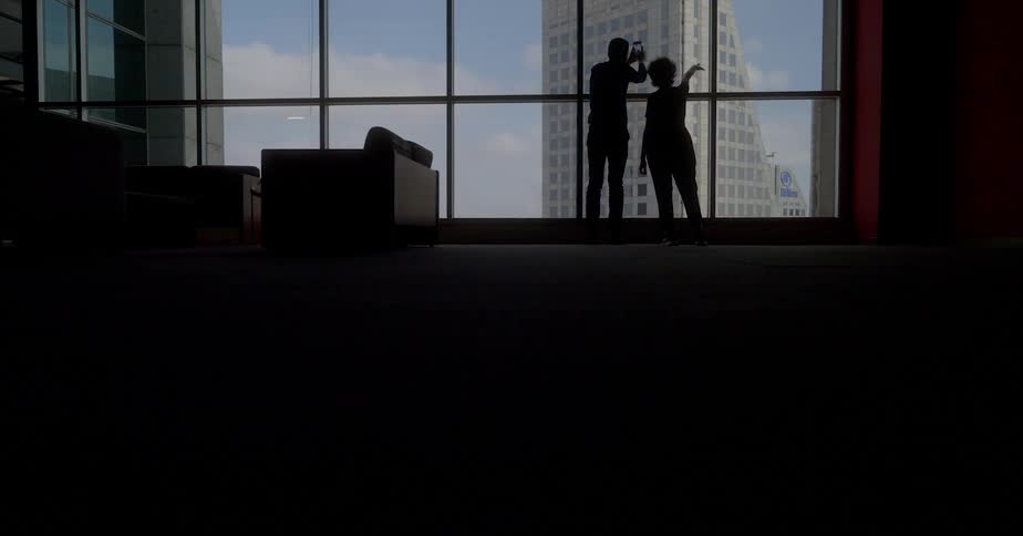 A couple take photos of the city skyline from their high rise apartment window