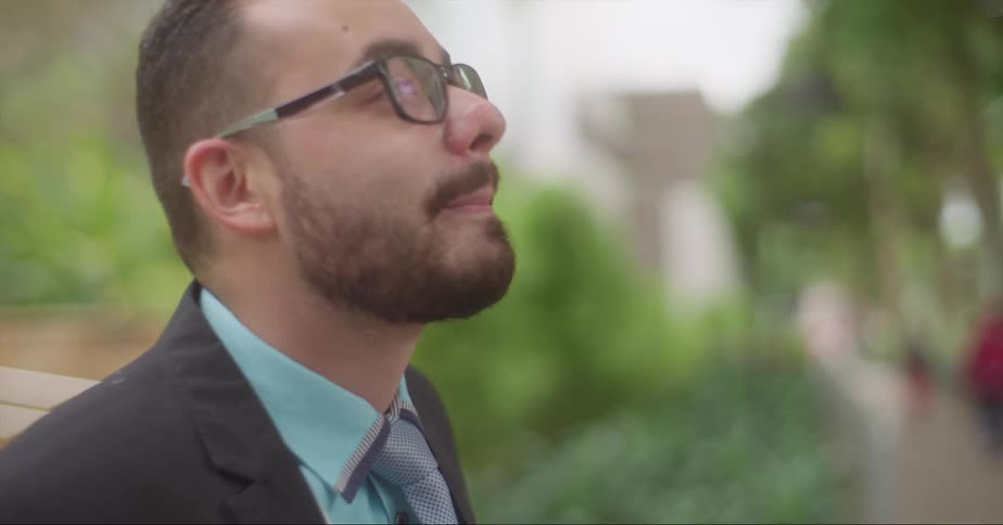 A man smiles and moves back a bit as he looks for and waits for someone