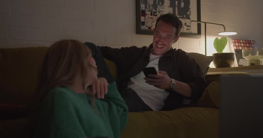 A man and woman talk by the couch on a date