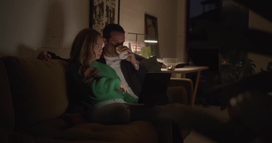 A couple sit on the couch talking at night